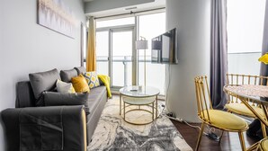 Un salon moderne avec un canapé, une table ronde et un téléviseur fixé au mur.