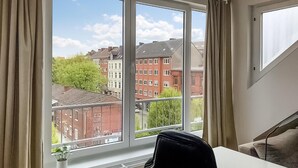 Een kamer met een groot raam, een witte tafel en een zwarte stoel.