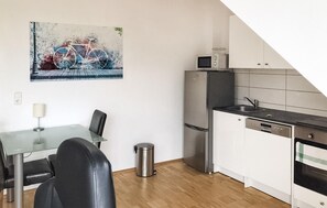 Een koelkast, een kookplaat, een vaatwasser, kookgerei, borden en bestek