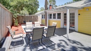 Eine Terrasse mit Tisch und Stühlen, ein Holzdeck und ein gelbes Gebäude mit Fenstern.