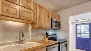 Eine Küche mit Holzausstattung, einer Edelstahl-Mikrowelle, einem Geschirrspüler und einem Kombi-Backofen.