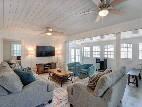 A spacious living room with a large TV, comfortable seating, and a fireplace.