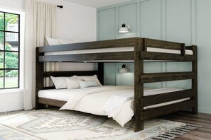 A bunk bed with a wooden frame, white bedding, and a patterned rug.