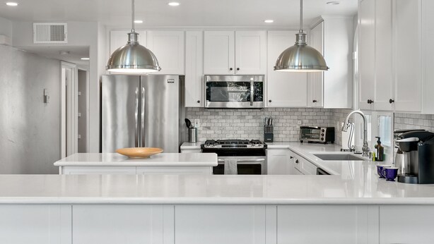 A modern kitchen with white cabinetry, stainless steel appliances, and pendant lighting. - Luxury Beach Home with Gas Fireplace, Fast WiFi, BBQ & Outdoor Seating (San Diego)