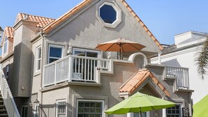 A multi-story building with a unique architectural design, including a balcony with a white railing and a large octagonal window. - Luxury Beach Home with Gas Fireplace, Fast WiFi, BBQ & Outdoor Seating (San Diego)