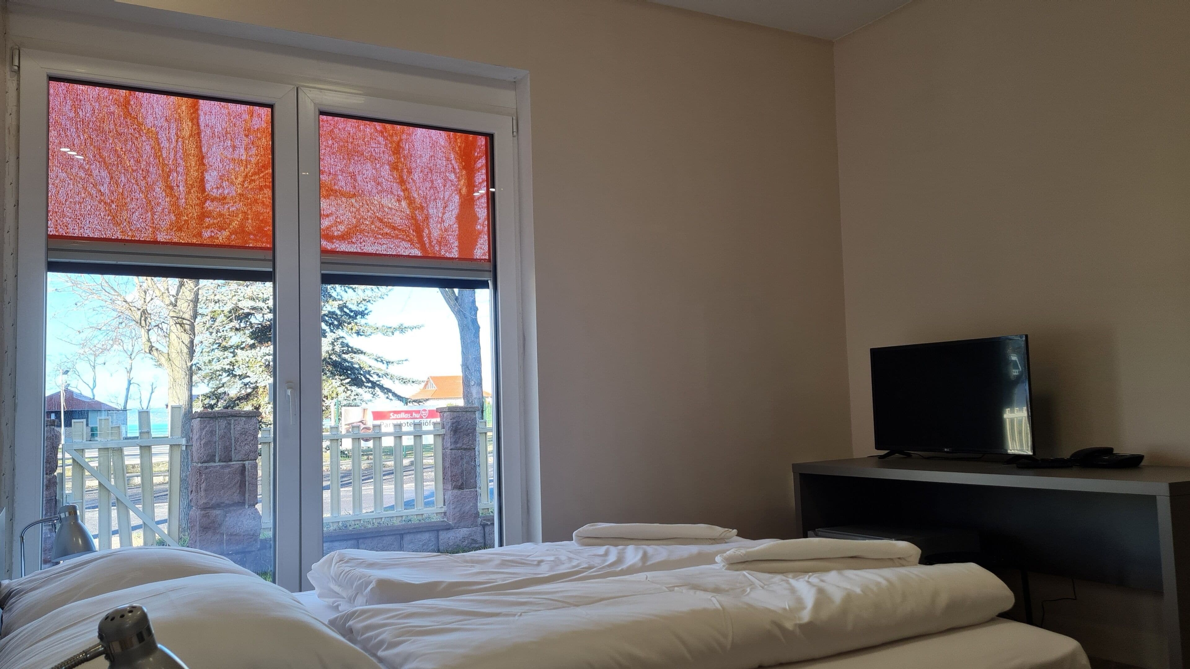 Habitación de hotel con cama, televisor y ventana con vistas al exterior.