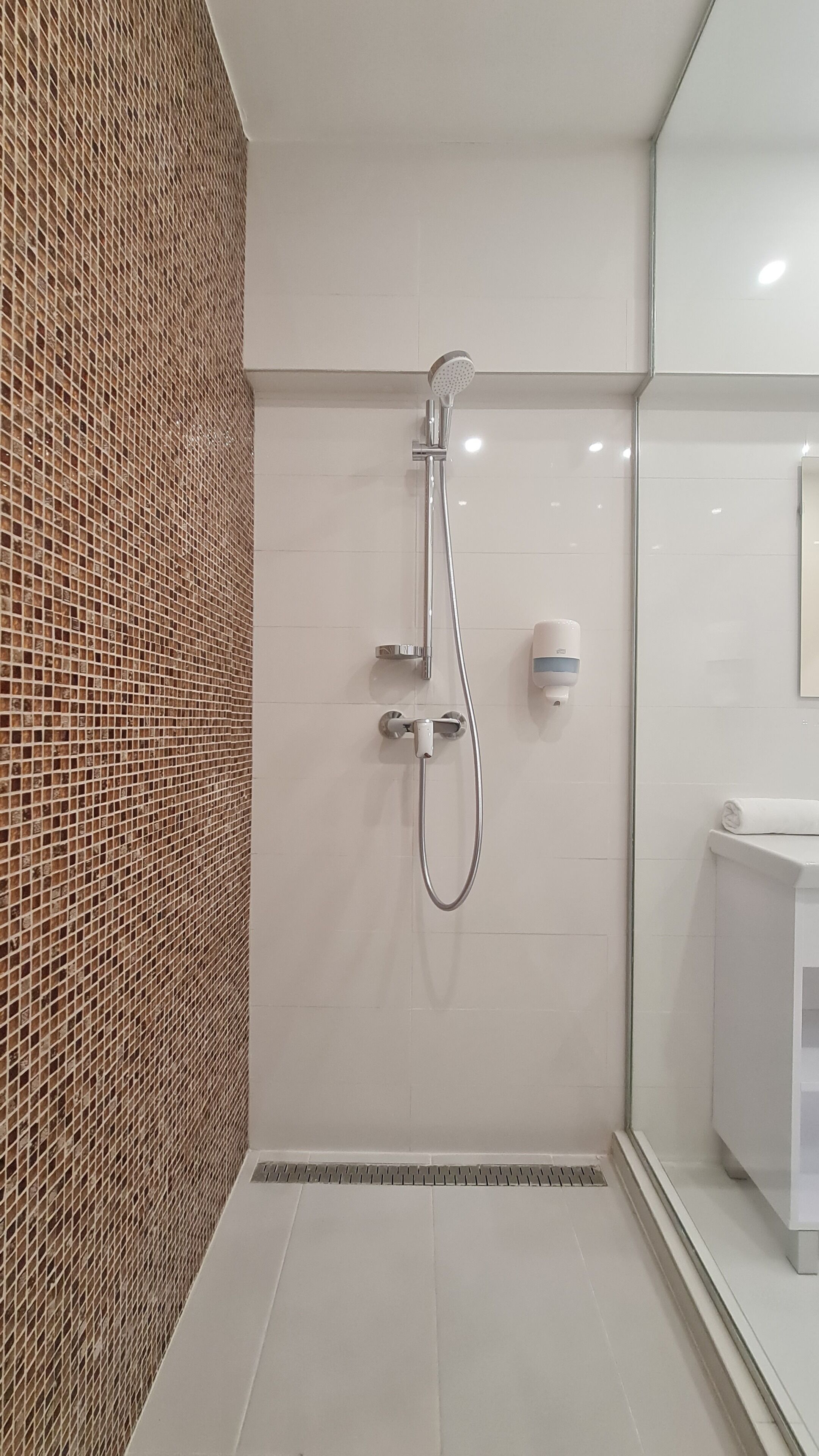 A modern bathroom with a shower, tiled walls, and a white sink.