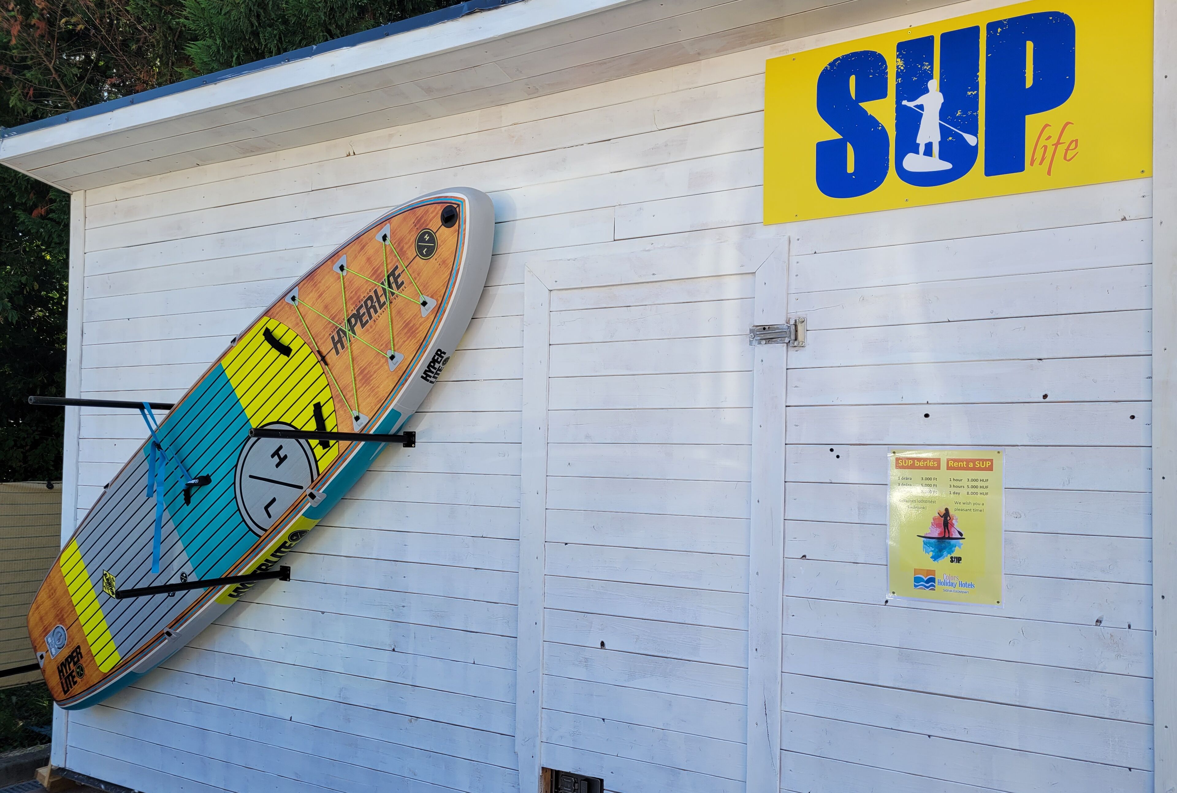 Une planche de stand-up paddle et une planche de surf appuyées contre un bâtiment.