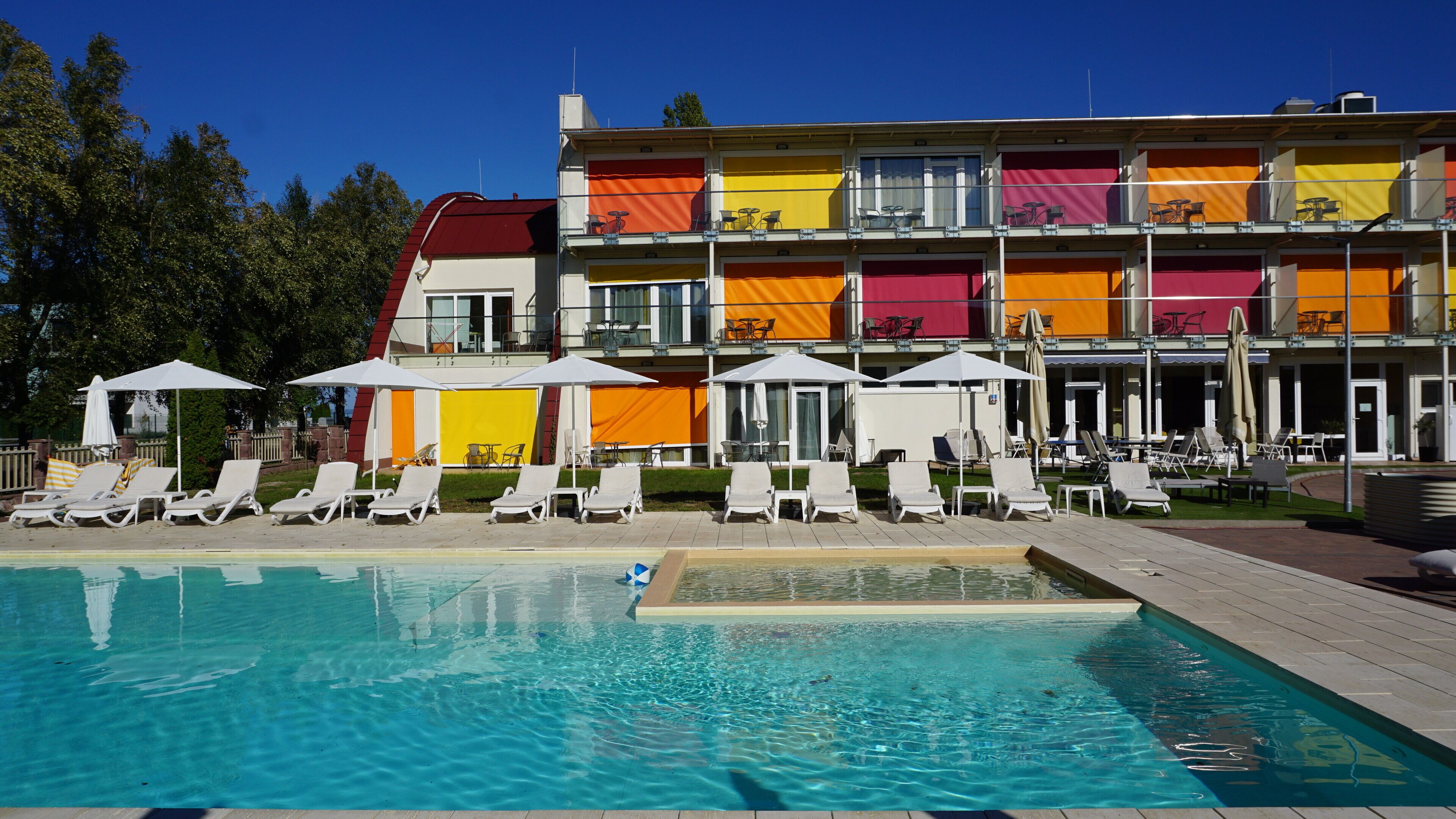 Et hotel med swimmingpool, liggestole og parasoller.
