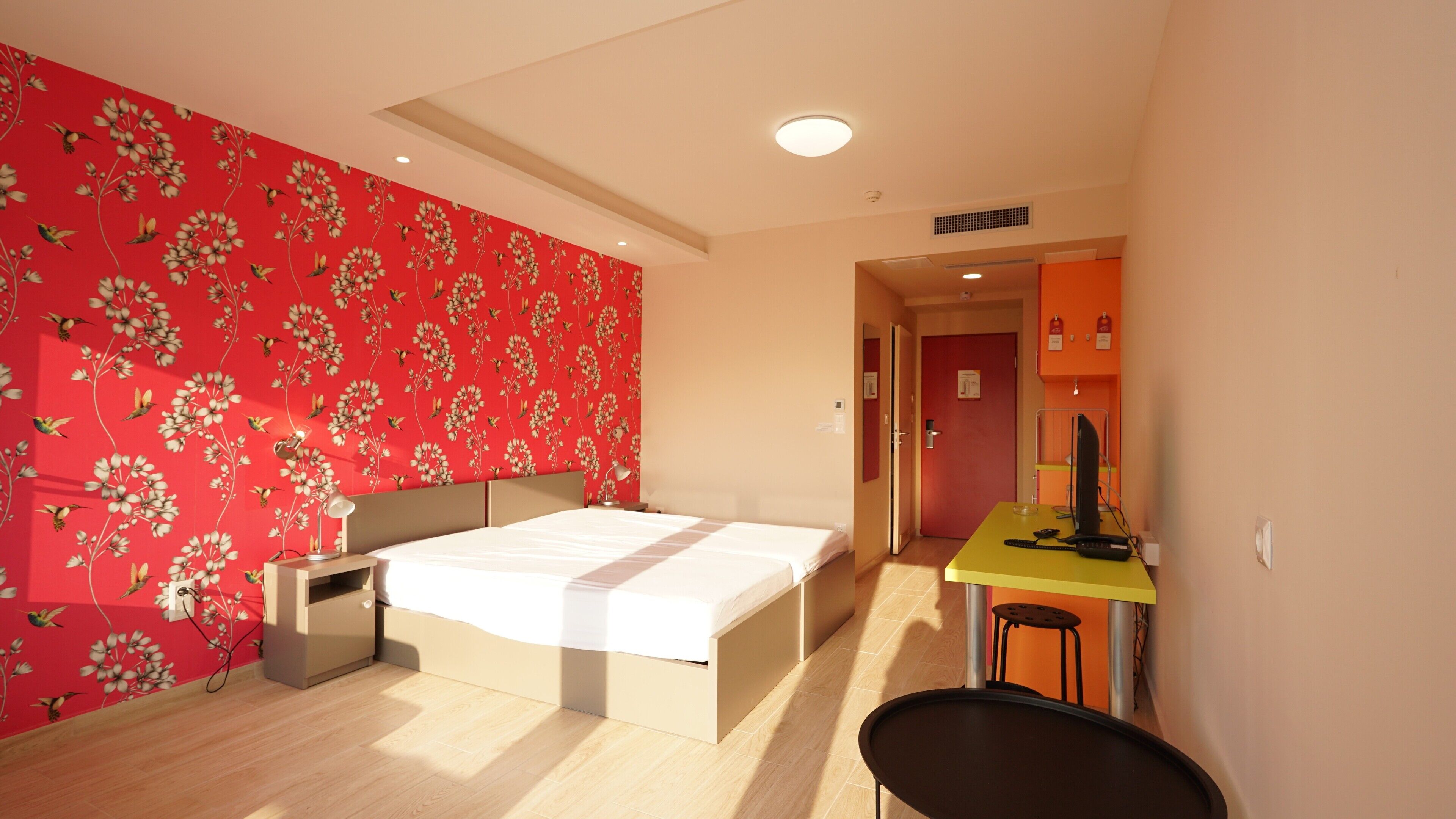 A bedroom with a bed, a desk, and a chair.