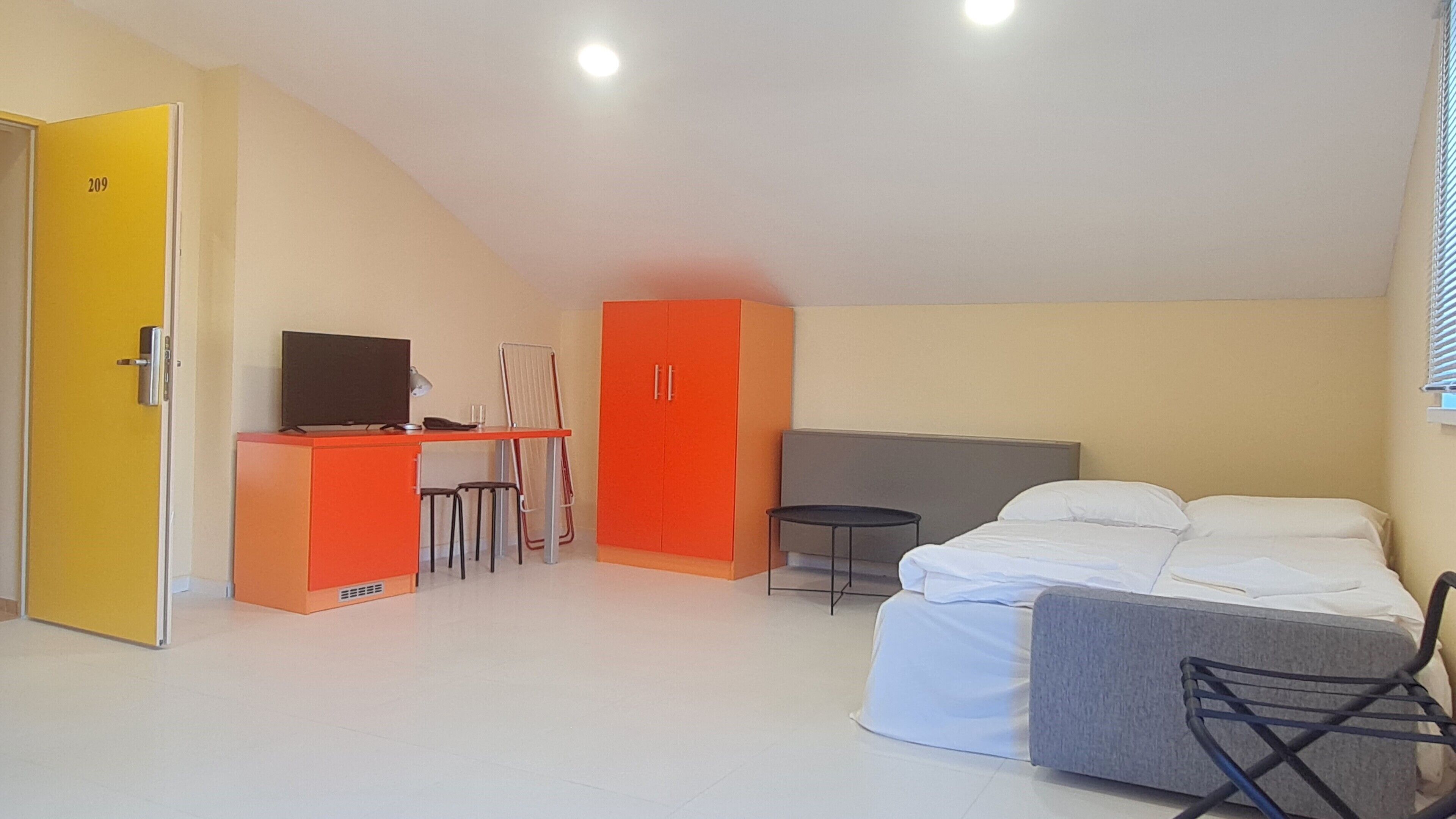 A room with a bed, a desk with a computer, a chair, and a wardrobe.