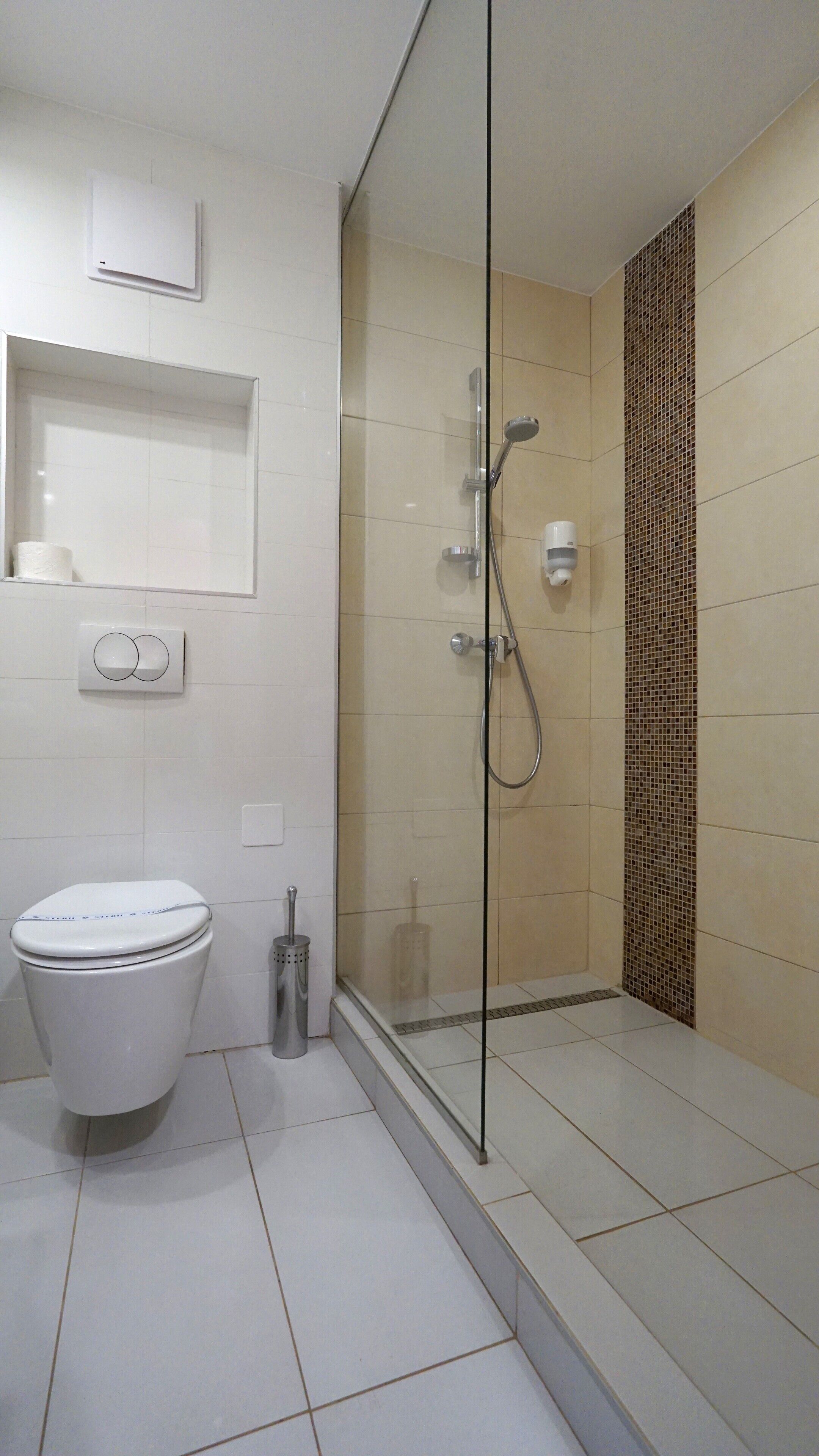 Un baño moderno con ducha de mampara de vidrio, inodoro y lavamanos.