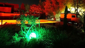 A nighttime scene with a well-lit pathway, a vehicle, and a building with illuminated windows.