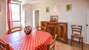 A dining area with a red polka dot tablecloth, wooden chairs, a cabinet with decorative carvings, and two wall-mounted pictures. - Cozy home in Malaucène (Malaucène)
