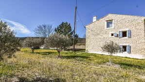 A stone house with a small window and a door, surrounded by a grassy area with trees and a clear sky. - Cozy home in Malaucène (Malaucène)