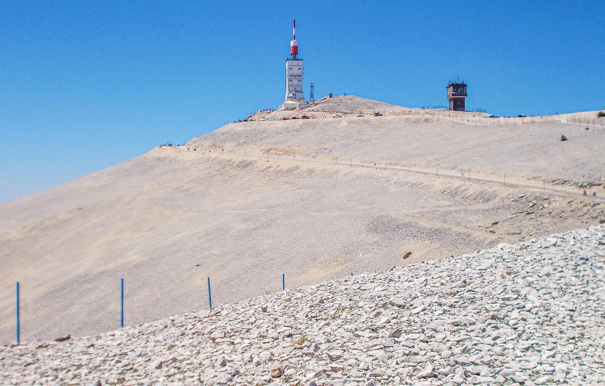 A rocky hill with a tall structure on top, possibly a communication tower, and a smaller building nearby.