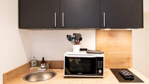 A compact kitchen with a microwave, sink, and black cabinets. - Nice little studio near Opera (Lyon)