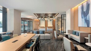 A modern hotel lobby with a long reception desk, seating areas, and a large abstract painting on the wall. - Fairfield by Marriott Hangzhou Binjiang Puyan (Hangzhou)