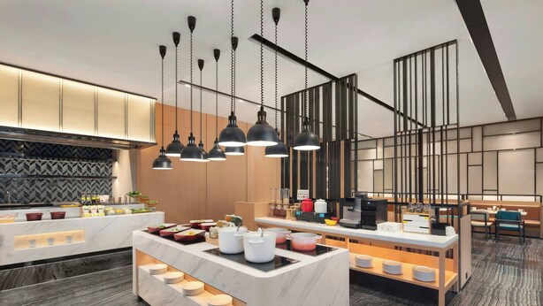 A modern kitchen with marble countertops, pendant lighting, and a central island with dishes. - Fairfield by Marriott Hangzhou Binjiang Puyan (Hangzhou)