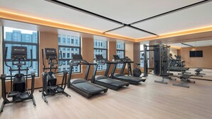 A modern gym with treadmills, ellipticals, and weight machines, large windows, and a mirror wall. - Fairfield by Marriott Hangzhou Binjiang Puyan (Hangzhou)