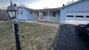 Ein Bungalow mit Garage, Veranda und Rasen.