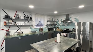 Eine moderne Küche mit grauen Schränken, einem Edelstahlkühlschrank und einer zentralen Kochinsel mit Barhocker.