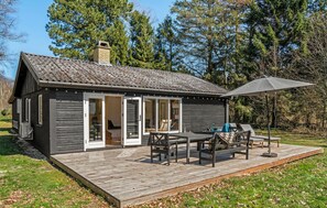 Une cabane dotée d’une terrasse, de meubles de jardin et d’une cheminée.