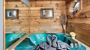 Eine Holzhütte mit Sauna, gerahmten Bildern an den Wänden und einem dekorativen Schwanentuch auf der Bank.