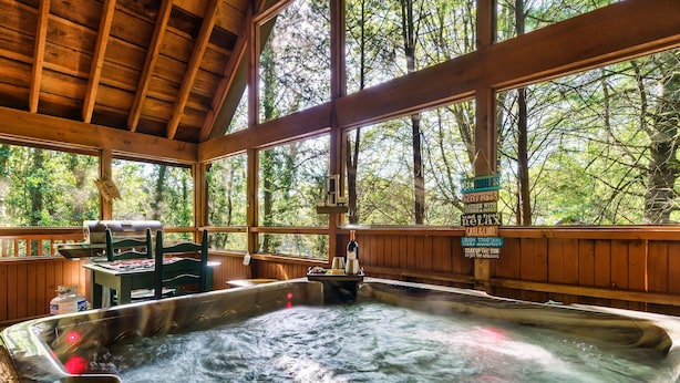 Ein Whirlpoolbereich mit Holzboden und großen Fenstern mit Blick auf einen Wald.