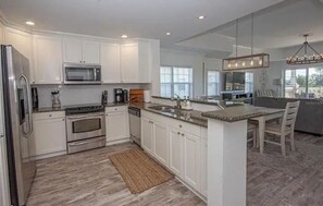 Enjoy cooking in this well-equipped kitchen with a large island, microwave, and stainless steel refrigerator.