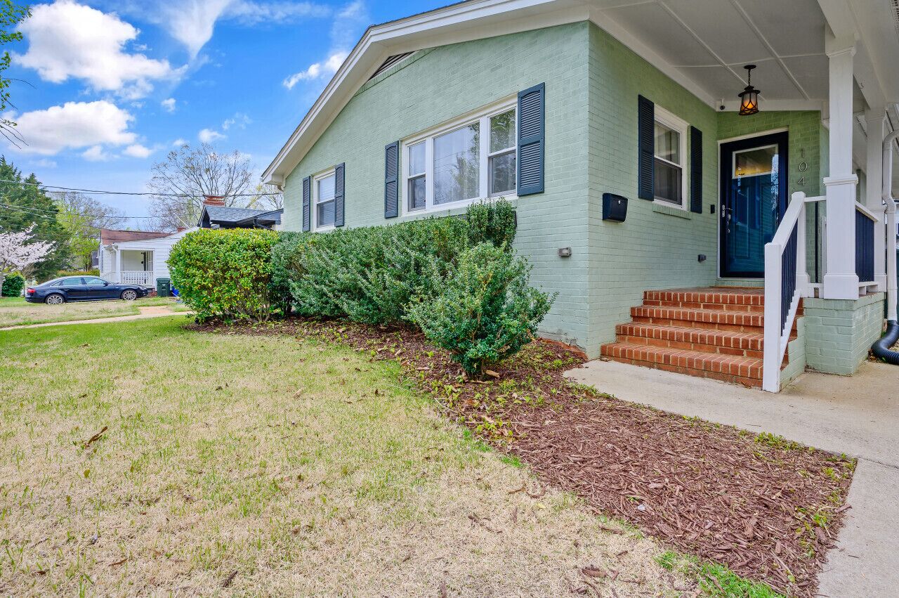A two-story house with a front porch, a small front yard, and a mailbox.