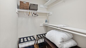 A small, neatly organized bedroom with a single bed, a hanging laundry rack, and storage shelves. - Charming 3-Bed Bungalow with Fenced-in Yard (Raleigh)