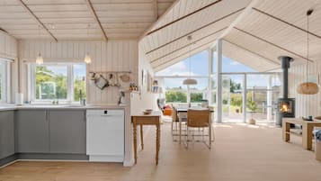 A spacious kitchen with a large island, wooden flooring, and a view to the outdoor patio area.