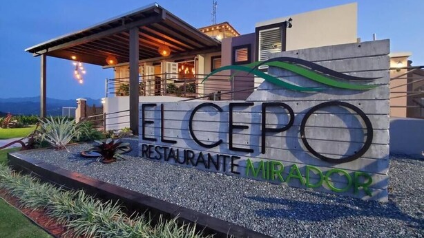 Moderni ravintolan kyltti, jossa lukee ”EL CEPO RESTAURANTE MIRADOR”, ja näkymä rakennuksen ulkopuolelle.