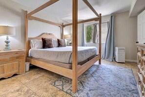 A four-poster bed with a wooden frame, a bedside table with a lamp, and a dresser with drawers. - Old Town Scottsdale- 2 Kings -Pool + Spa (Scottsdale)