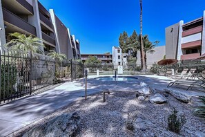A pool area with a concrete deck, surrounded by a fence and palm trees. - Old Town Scottsdale- 2 Kings -Pool + Spa (Scottsdale)
