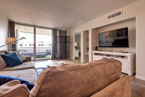 A living room with a sofa, a television, and a view of the outside.