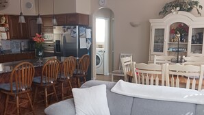 Ein Wohnzimmer mit grauem Sofa, Holzstühlen, einem kleinen runden Tisch und einem Deckenventilator.