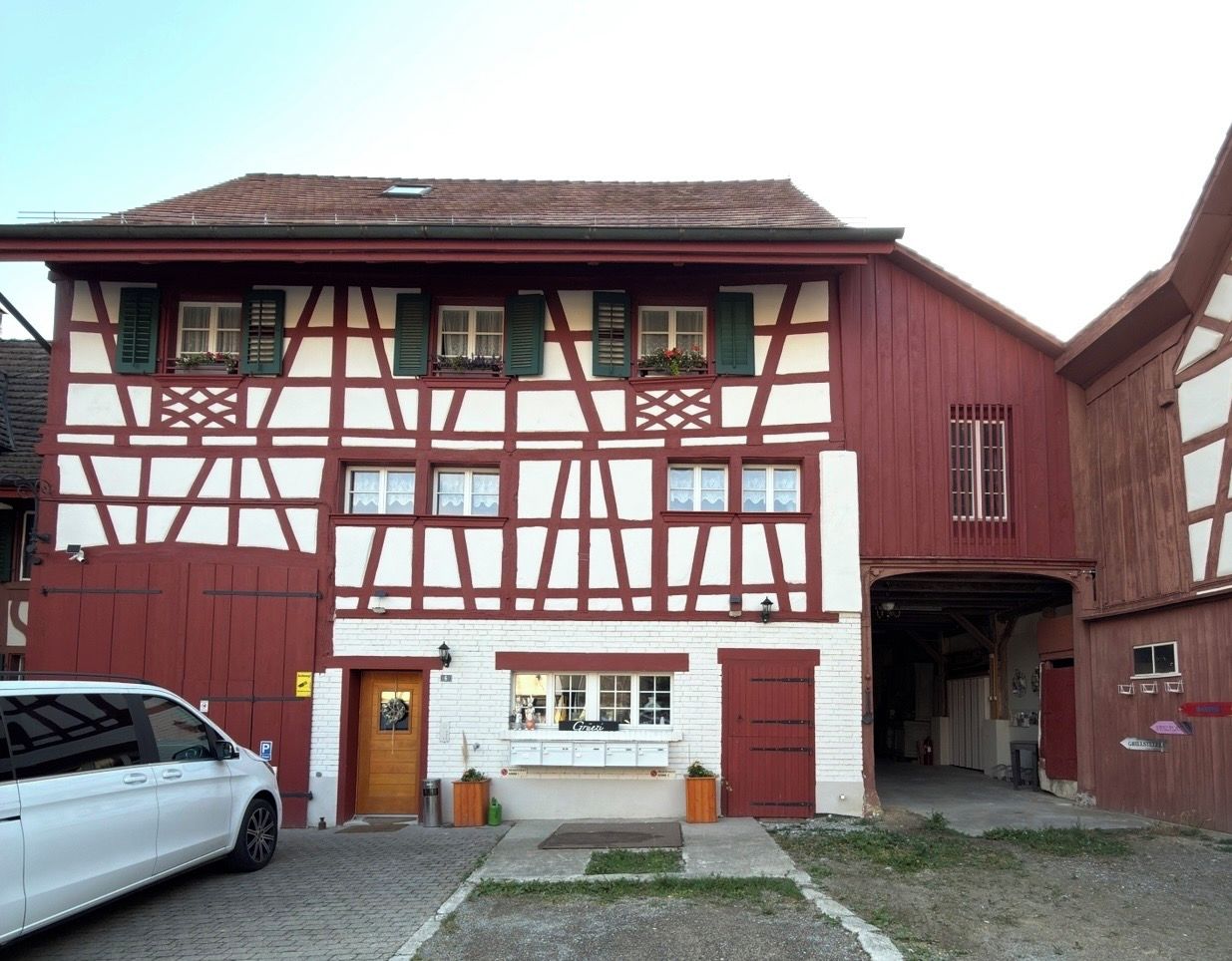 Ein traditionelles Fachwerkhäuschen mit einer Garage, einem kleinen Laden im Erdgeschoss und einem geparkten Auto davor.