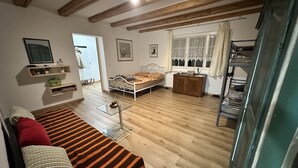 A cozy room with a wooden floor, a bed, a sofa, a glass coffee table, and a window with curtains. - Idyllischer Bauernhof 3 (Wildensbuch)