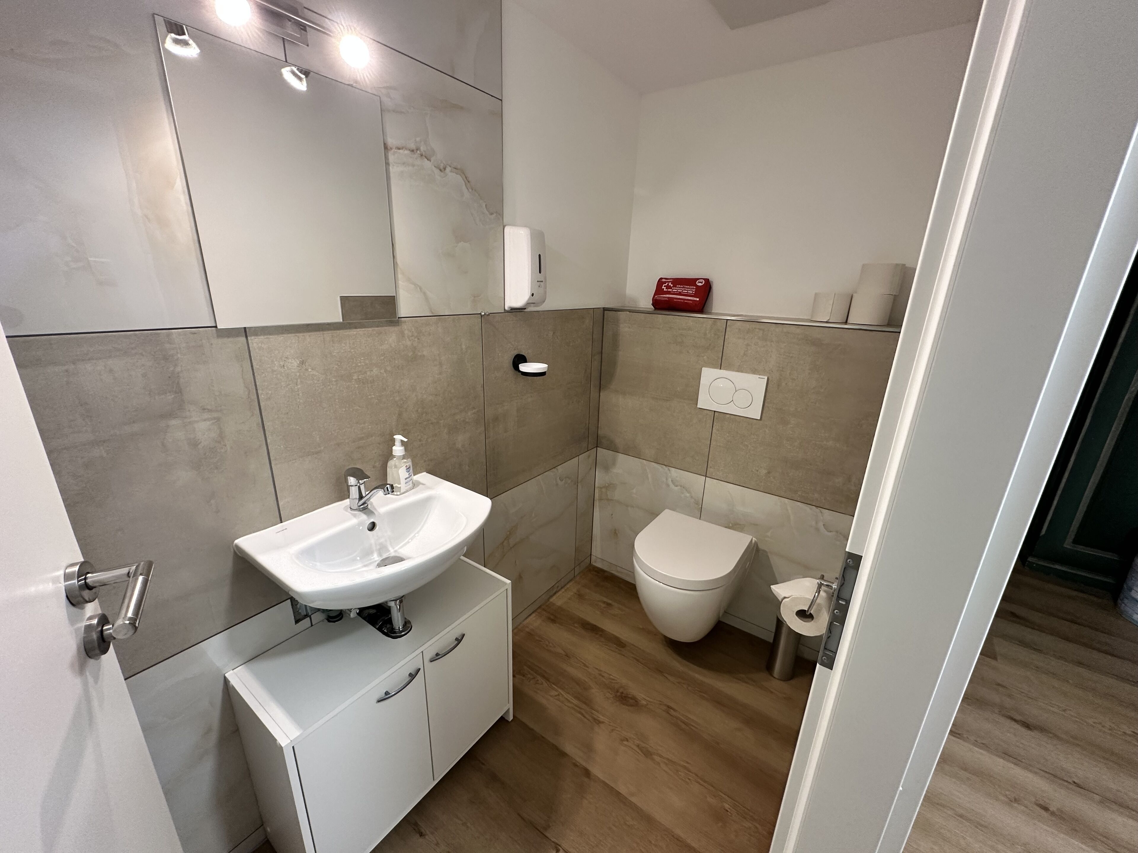 A modern bathroom with a white sink, a toilet, and a mirror.