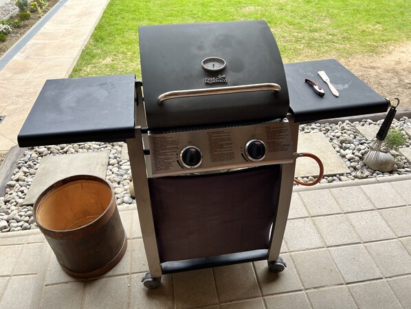 A portable grill with a digital thermometer, a control panel, and a side table with utensils.