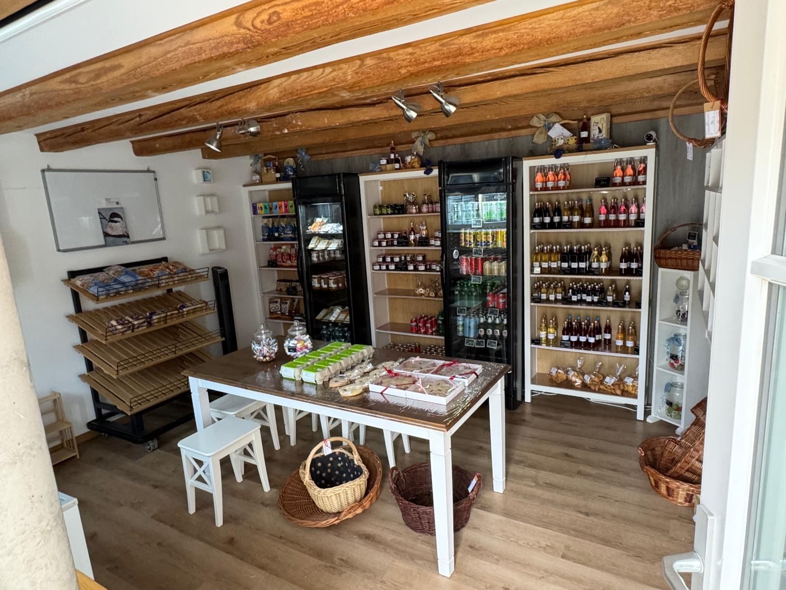 A store with wooden beams, shelves stocked with various products, and a table with baskets.