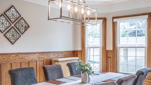 Uma sala de jantar com uma mesa de madeira, cadeiras e um lustre.