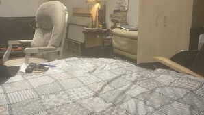 Ein Hotelzimmer mit Bett, Stuhl, Schreibtisch, Lampe und Kleiderschrank.
