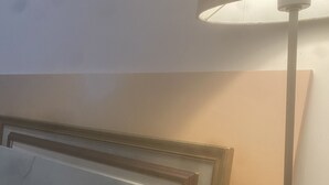 Ein Zimmer mit einem Bett, einer Lampe und einem Spiegel.