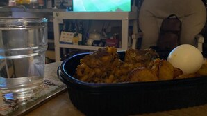Ein Esstisch mit Mahlzeit, einem Glas Wasser und einem Fernseher, der ein Sportevent zeigt.