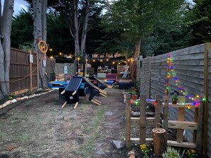 A backyard with a wooden fence, a slide, and string lights. - Octopus Lounge V.C Studio & Suites (London)