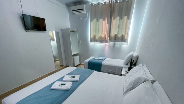 Habitación de hotel con dos camas, televisor, aire acondicionado y ventana con cortinas.