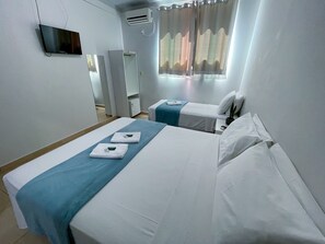 A hotel room with two beds, a TV, an air conditioner, and a window with curtains. - Hotel Dallas (Penha)